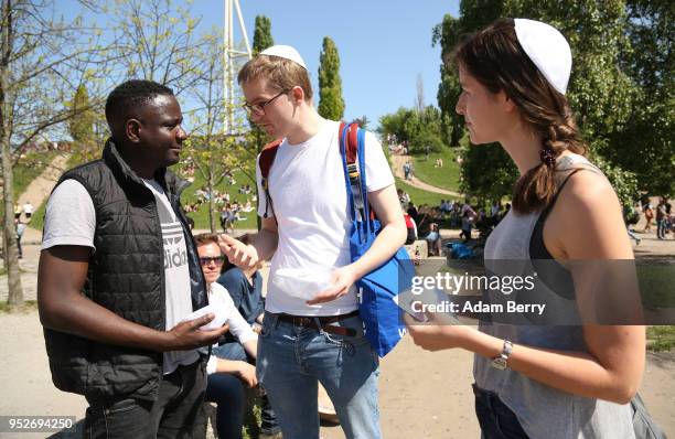 Volunteers hand out a kippah, or yarmulke, to a visitor to the Mauerpark public park during a day of demonstrations against antisemitism on April 29,...