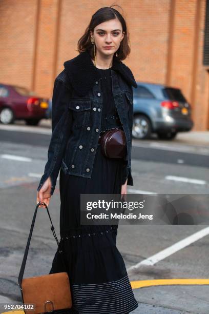 Model Milena Litvinovskaya wears a black denim jacket, black dress, leather purse around her waist, and ab brown 3.1 Phillip Lim paperclip bag on...