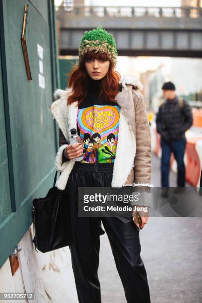Model Sasha Mart wears a green hat, bomber shearling jacket, Beatles "All You Need is Love" t-shirt, and black pants on February 8, 2018 in New York...