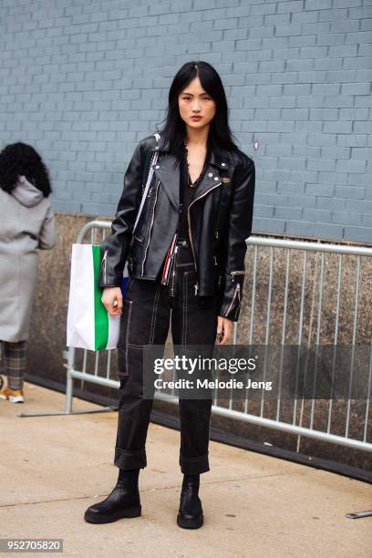 Model Jing Wen wears a black leather jacket, Thom Browne cardigan, black jeans, and black boots on February 9, 2018 in New York City.