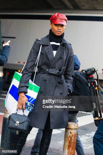Model Mayowa Nicholas wears a red leather conductor hat, black trench after the Tory Burch show on February 9, 2018 in New York City.