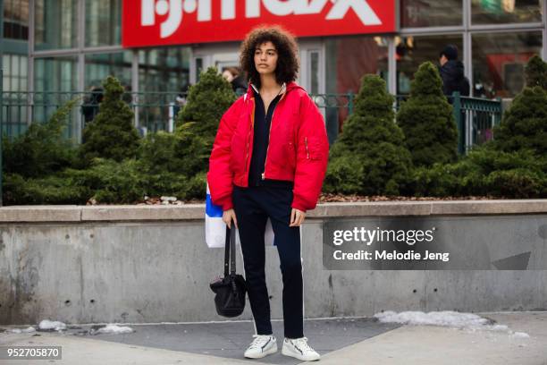 Model Shelby Hayes wears a red Vetements bomber jacket, Tory Sport dark blue tracksuit, and white Tory Sport sneakers, and a black Loewe bag after...