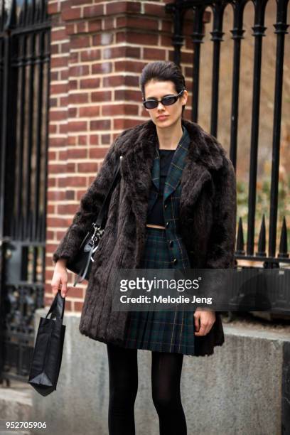 Model Taja Feistner wears futuristic Matrix-style sunglasses, a brown fur jacket, a green plaid jacket and skirt, and black tights on February 9,...