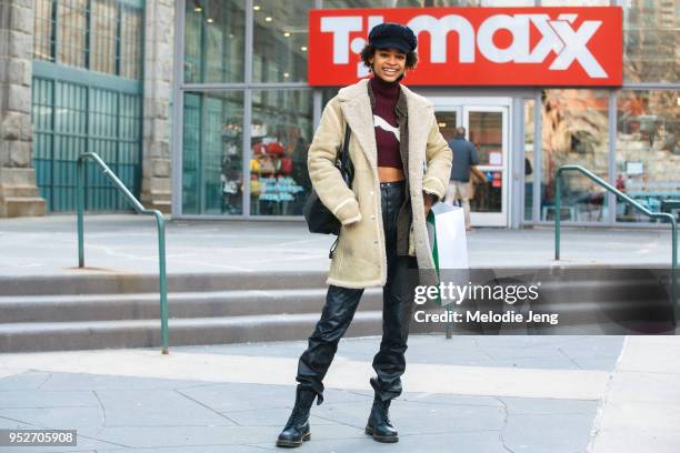 Model Theresa Hayes wears a blue conductor hat, a light shearling coat, Fenty x Puma logo croptop, black leather pants, black Doc Marten boots after...