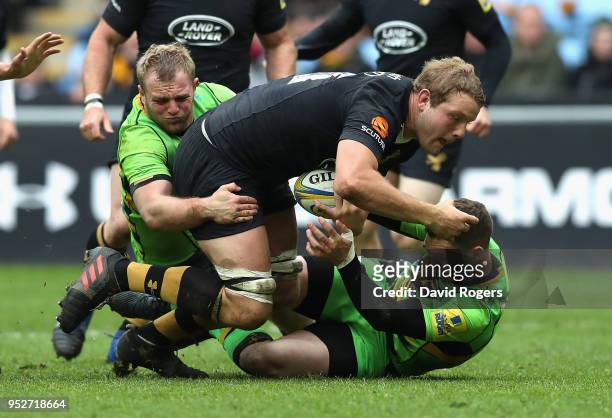 Joe Launchbury of Wasps is stopped by Mikey Haywood and George North during the Aviva Premiership match between Wasps and Northampton Saints at The...