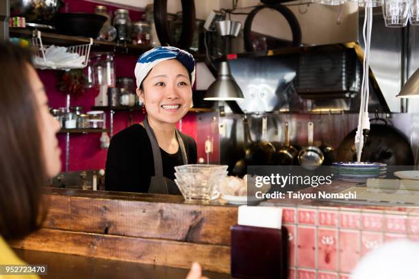 a woman chef talking to the customer from the kitchen - cafe culture stock pictures, royalty-free photos & images