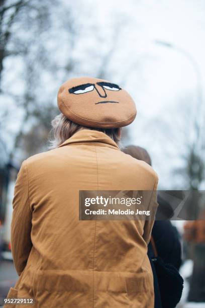 Guest wears a tan beret with a face on the top on January 26, 2018 in Oslo, Norway.