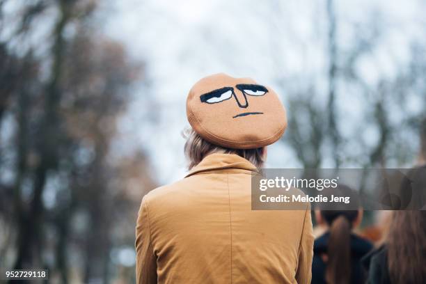 Guest wears a tan beret with a face on the top on January 26, 2018 in Oslo, Norway.