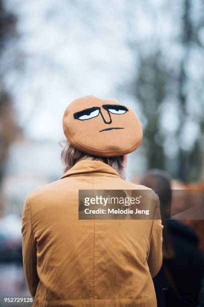 Guest wears a tan beret with a face on the top on January 26, 2018 in Oslo, Norway.