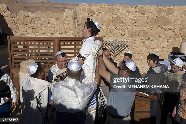 Members of a Jewish family lift a boy as they dance during his Bar Mitzvah ceremony in the ancient synagogue of the hilltop fortress of Masada in the...