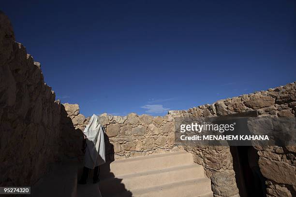 An ultra-Orthodox Jewish man wrapped in a talit, a prayer shawl, prays in the ancient synagogue at the hilltop fortress of Masada in the Judean...