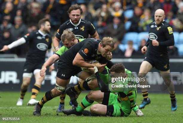 Joe Launchbury of Wasps is tackled by Mikey Haywood and George North during the Aviva Premiership match between Wasps and Northampton Saints at The...