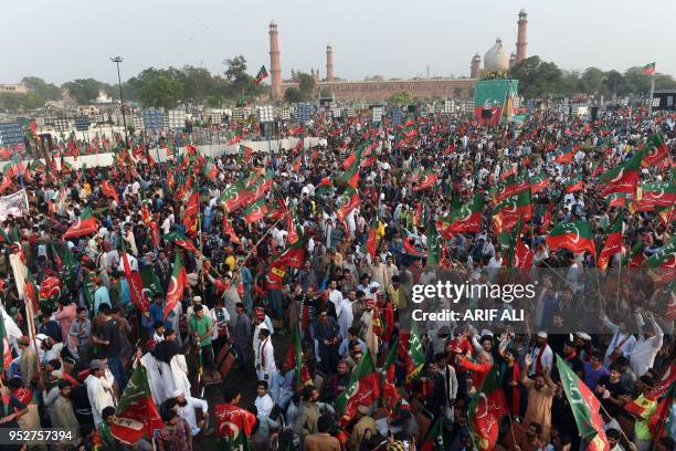 Supporters gesture and wave flags of the Pakistani political party Pakistan Tehreek-e-Insaf as they attend a rally with Pakistan opposition leader...