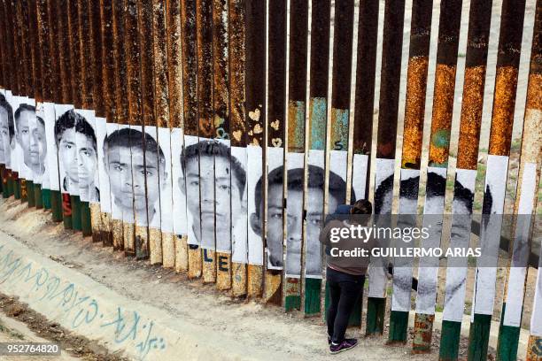 Central American migrant with her kid travelling in the "Migrant Via Crucis" caravan looks through the US/Mexico Border at Tijuana's beaches, Baja...