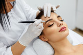 Beautician Doing Permanent Eyebrows Makeup Tattoo On Woman Face