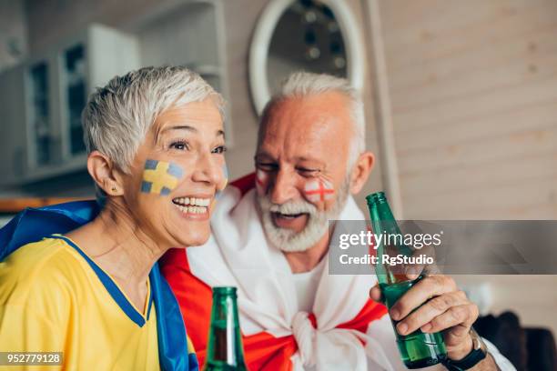 rijpe vrouw ter ondersteuning van de zweedse nationale voetbalspel en man ter ondersteuning van engeland - geschminkt gezicht stockfoto's en -beelden