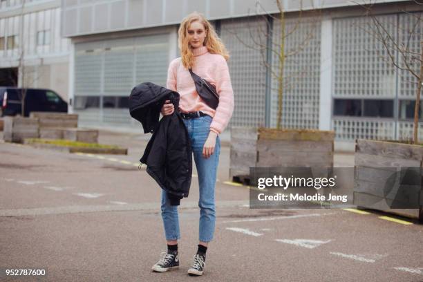 Model Pernille Kristiansen wears a pink sweater, fanny pack, jeans, and black Converse sneakers at Copenhagen Fashion Week Autumn/Winter 18 on...