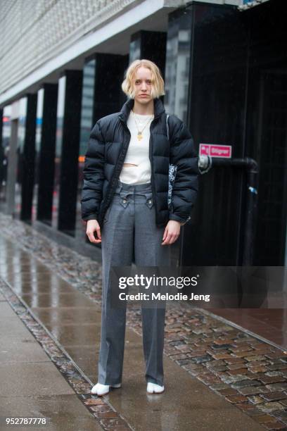 Model Clara Thorndahl wears a black down jacket, white top with a slit, gray trousers, and white Margiela tabi boots at Copenhagen Fashion Week...