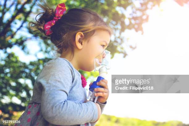 girl using asthma inhaler in a park - childhood asthma stock pictures, royalty-free photos & images