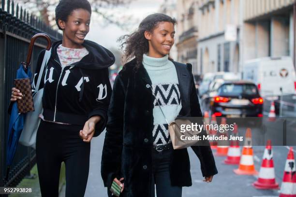Models Imari Karanja, Alyssa Traore on January 22, 2018 in Paris, France. Imari holds a Louis Vuitton monogrammed wallet and blue umbrella. Alyssa...