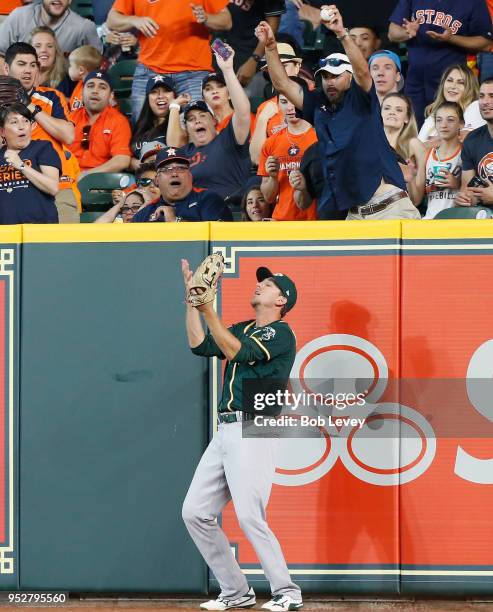 Stephen Piscotty of the Oakland Athletics leaps for a ball hit by Max Stassi of the Houston Astros in the fifth inning but is interfered with by a...