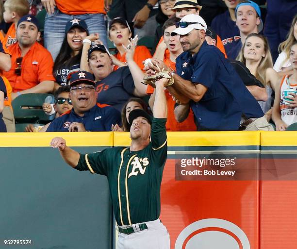 Stephen Piscotty of the Oakland Athletics leaps for a ball hit by Max Stassi of the Houston Astros in the fifth inning but is interfered with by a...