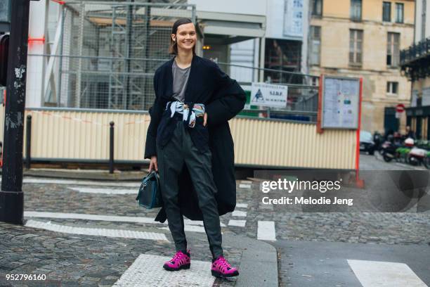 Model Daniela Kocianova wears a dark blue coat, gray shirt, dark gray pants, scarf around her waist, Celine bag, and pink Supreme Nike ACG sneakers...