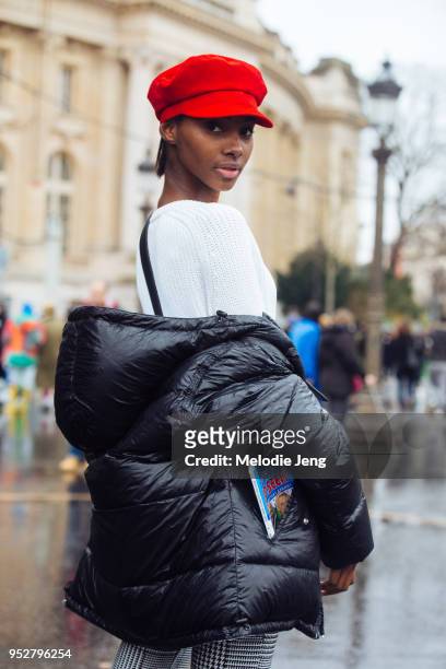 Model Tami Williams wears a red beret, white sweater, and black jacket, and looks over her shoulder after the Chanel show on January 23, 2018 in...
