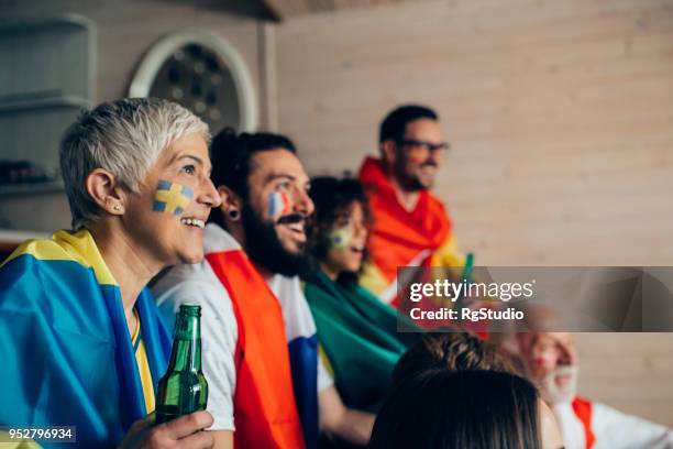 rijpe vrouw steunt zweedse voetbalteam spel kijken met vrienden ter ondersteuning van andere nationale teams - soccer germany stockfoto's en -beelden