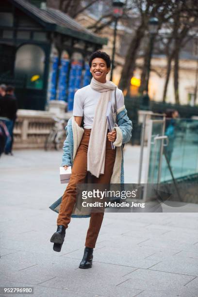 Model Jourdana Phillips wears a light pink scarf, white tshirt, denim coat, brown pants, and black booties on January 24, 2018 in Paris, France.