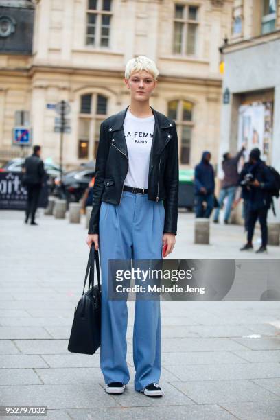 Model Sarah Fraser wears a black cropped leather jacket, "La Femme Paris" white t-shirt, and light blue loose trousers on January 24, 2018 in Paris,...