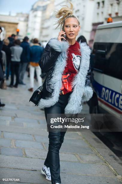 Model Soo Joo Park rushes out of the Jean Paul Gaultier show on her phone in the eye makeup from the show, wearing a black leather jacket with light...