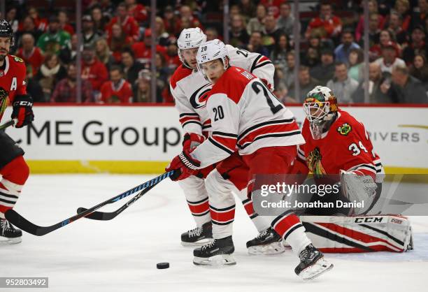 Sebastian Aho of the Carolina Hurricanes tries to control a pass in front of teammate Lee Stempniak and J-F Berube of the Chicago Blackhawks at the...