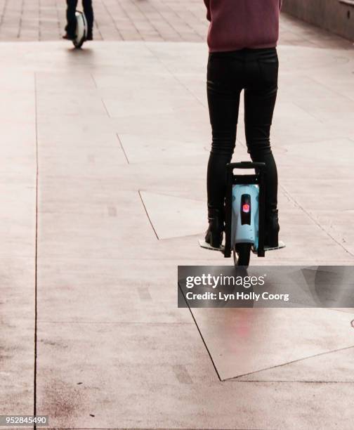 rear view of woman's legs on electric unicycle riding along sidewalk - lyn holly coorg fotografías e imágenes de stock