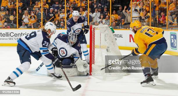 Connor Hellebuyck of the Winnipeg Jets makes the save against Nick Bonino of the Nashville Predators as Patrik Laine defends in Game Two of the...