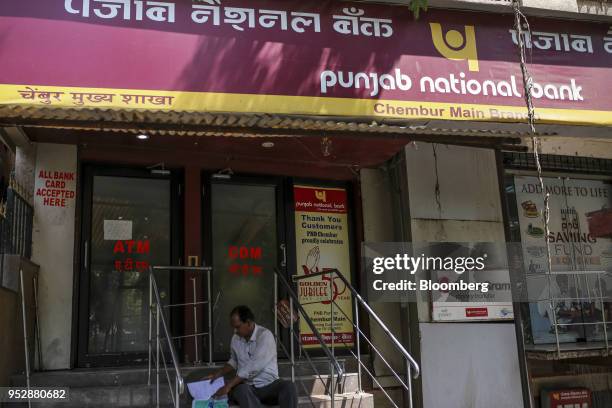 Man sits on steps outside a Punjab National Bank branch in Mumbai, India, on Saturday, April 21, 2018. PNB is scheduled to announce full year...