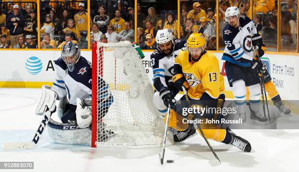 Nick Bonino of the Nashville Predators battles behind the net against Dustin Byfuglien of the Winnipeg Jets as goalie Connor Hellebuyck tends net in...