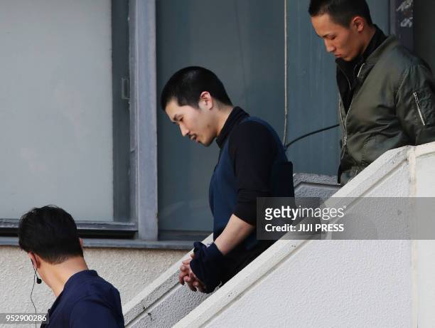 Japanese fugitive Tatsuma Hirao is escorted as he leaves a police department in Hiroshima after he was arrested on April 30, 2018. - Japanese police...