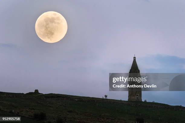 Couple watch the Pink Moon rise beside Hartshead Pike on April 29, 2018 in Manchester, England. The tower was rebuilt in 1863 by John Eaton to...