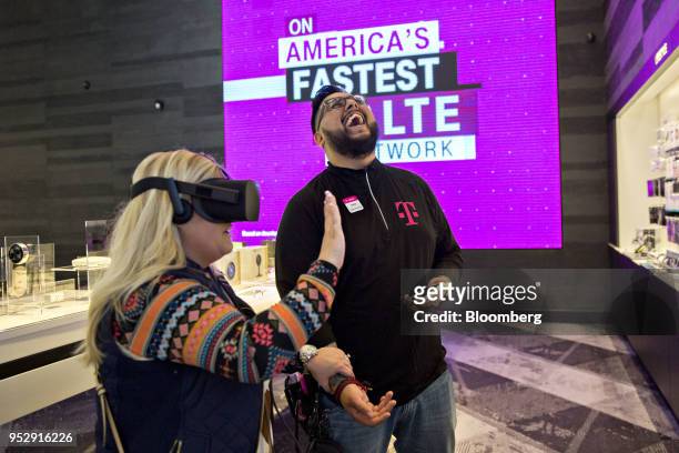 An employee reacts as a shopper tests an Oculus Rift virtual reality headset at a T-Mobile US Inc. Store in Chicago, Illinois, U.S., on Friday, Oct....