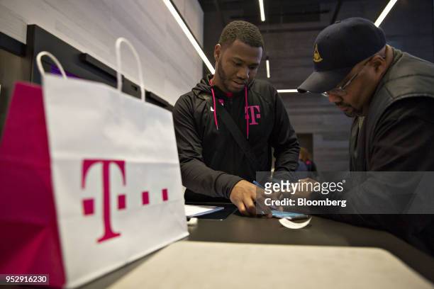 An employee assists a customer at a T-Mobile US Inc. Store in Chicago, Illinois, U.S., on Friday, Oct. 21, 2016. T-Mobile US Inc. Agreed to acquire...
