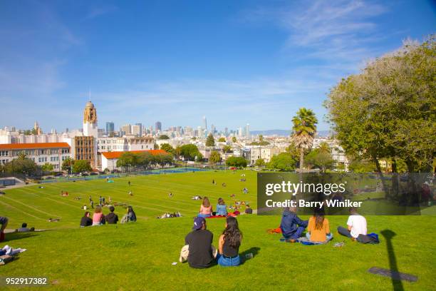 lawn filled with people enjoying a sunny day in san francisco's mission dolores park - dolores park imagens e fotografias de stock