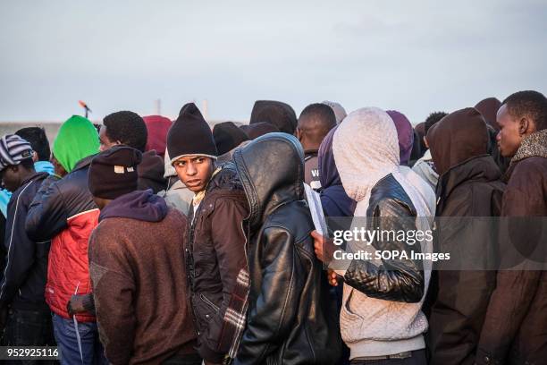 Refugees and migrants stand in line waiting to leave the Calais Jungle during the evacuation. The Jungle was an illegal migrant camp in the northern...