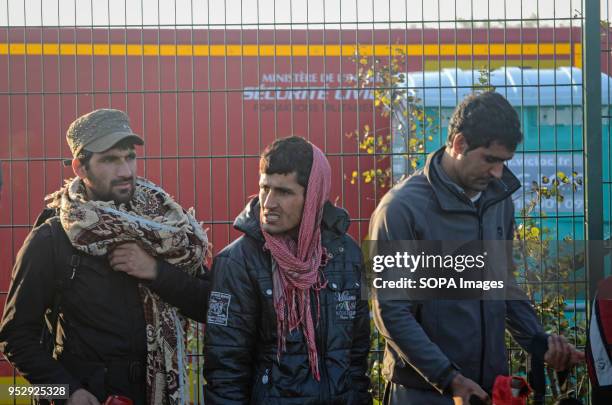 Refugees and migrants stand in line waiting to leave the Calais Jungle during the evacuation. The Jungle was an illegal migrant camp in the northern...