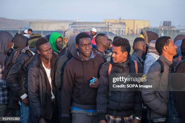 Refugees and migrants stand in line waiting to leave the Calais Jungle. The Jungle was an illegal migrant camp in the northern French town of Calais....