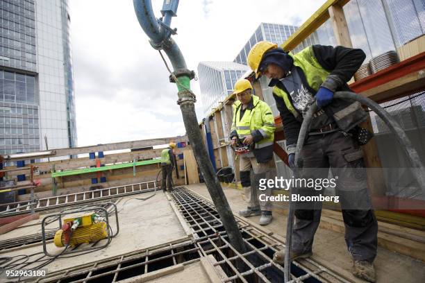 Construction worker holds a pipe as concrete is pumped into an elevator shaft of the Omiturm mixed-use 45-story residential and office tower block,...