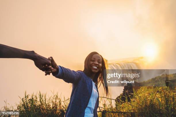 beautiful african girl holding hands with victoria falls background - victoria falls stock pictures, royalty-free photos & images