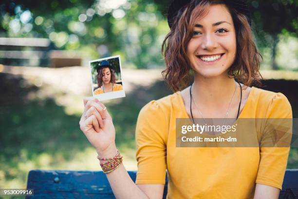 lächelnde frau zeigt polaroid selfie zur kamera - waist up photos stock-fotos und bilder