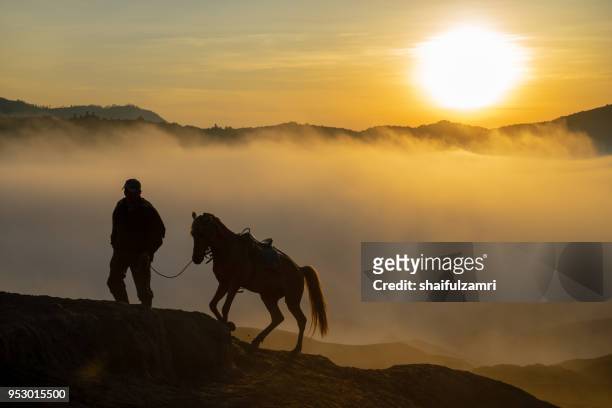 silhouette of unidentified local people or bromo horseman at mountainside of mount bromo, semeru, tengger national park, indonesia - bromo horse stock pictures, royalty-free photos & images