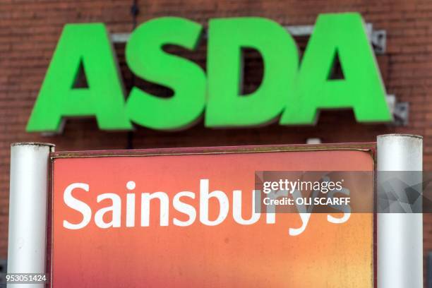 Logos of supermarket chains Asda and Sainsbury's are pictured outside adjacent branches of their stores in Stockport, northern England on April 30,...